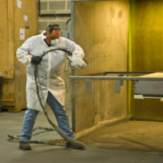 A Matot worker sprays part of a dumbwaiter with a finishing solution.